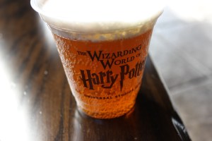 Close up of cup containing frothy yellow soft drink. Text on cup reads 'The Wizarding World of Harry Potter Universal Studios Osaka'