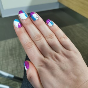 A right hand displaying blue, pink and white patterned nail polish.