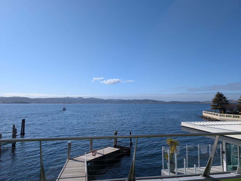 Outdoor view of a sunny day, view over open water, with hills in the background