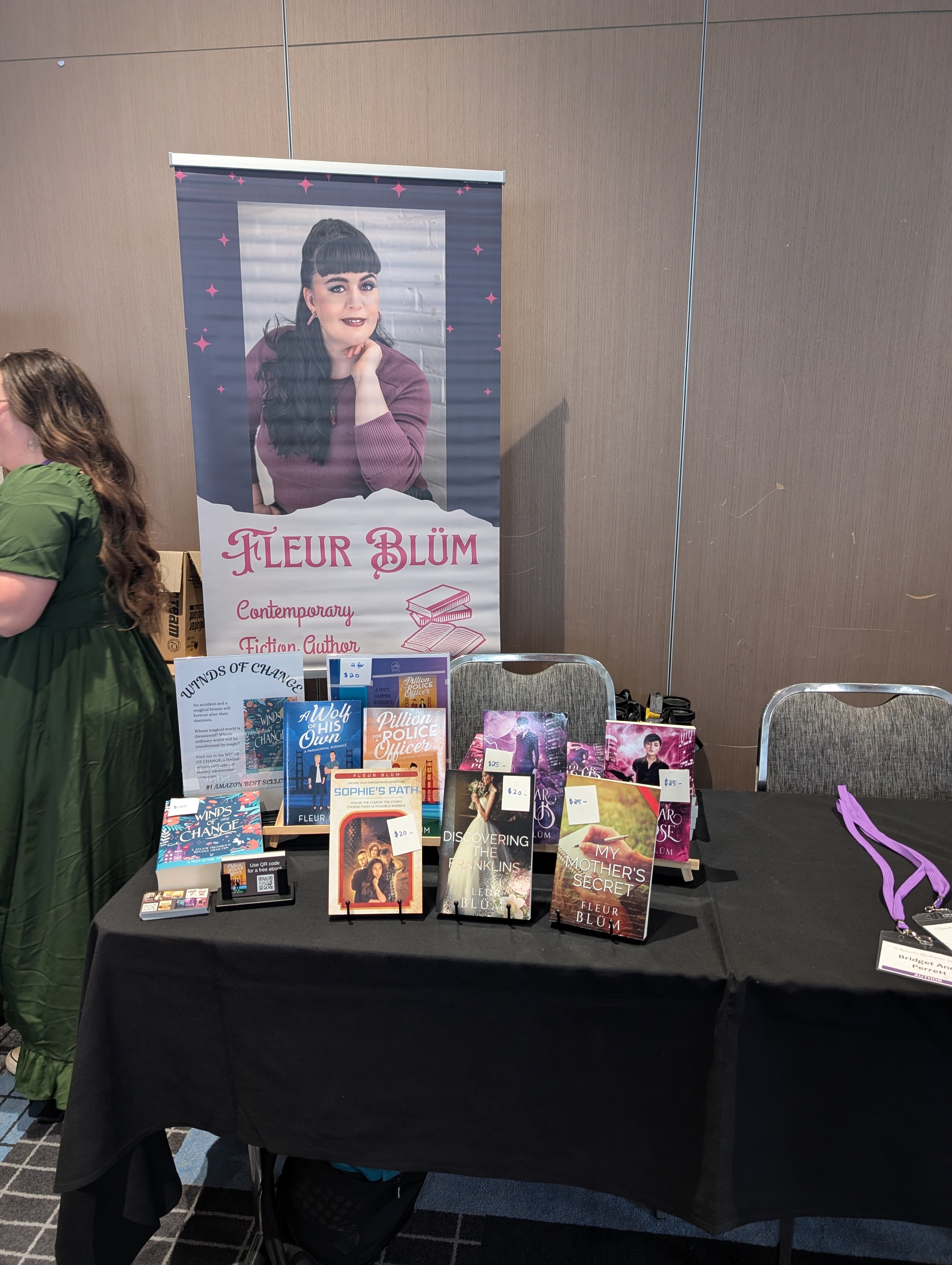 A table shows a display of books, behind the table is a banner with Fleur's face and name