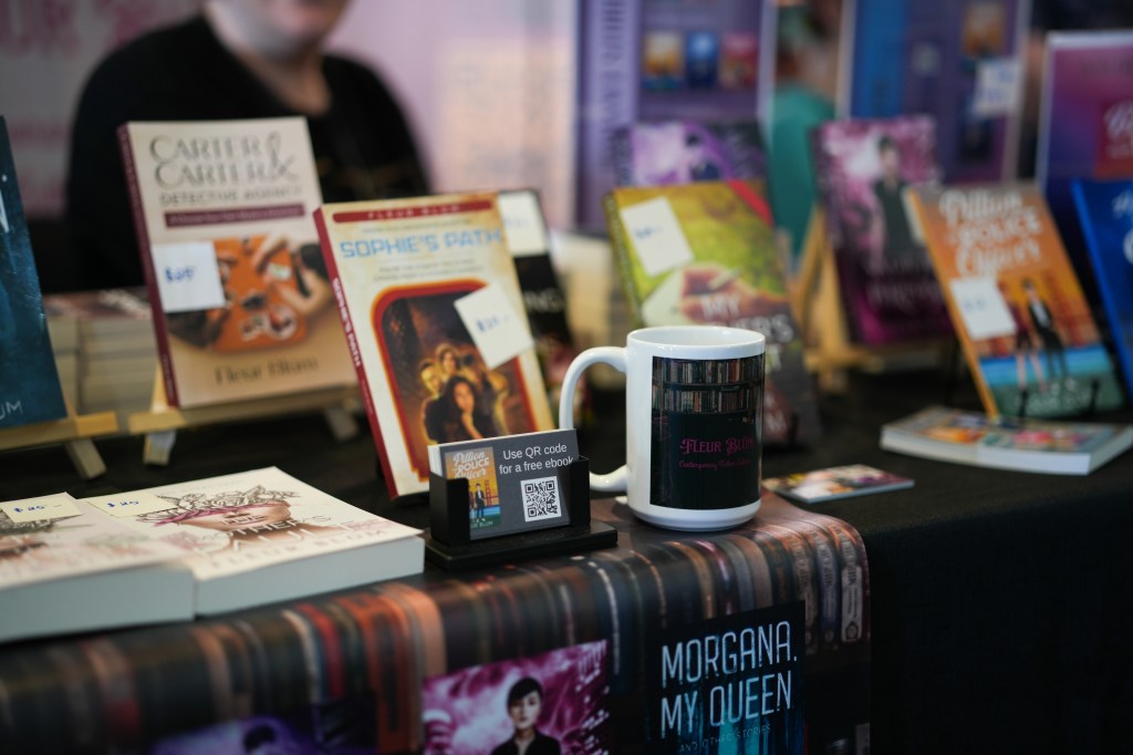 Books and a mug are displayed on a table with a black table cloth.
